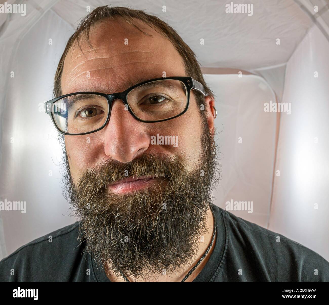 Ein bärtig lächelnder Mann in guter Stimmung mit Schwarz Brille Stockfoto