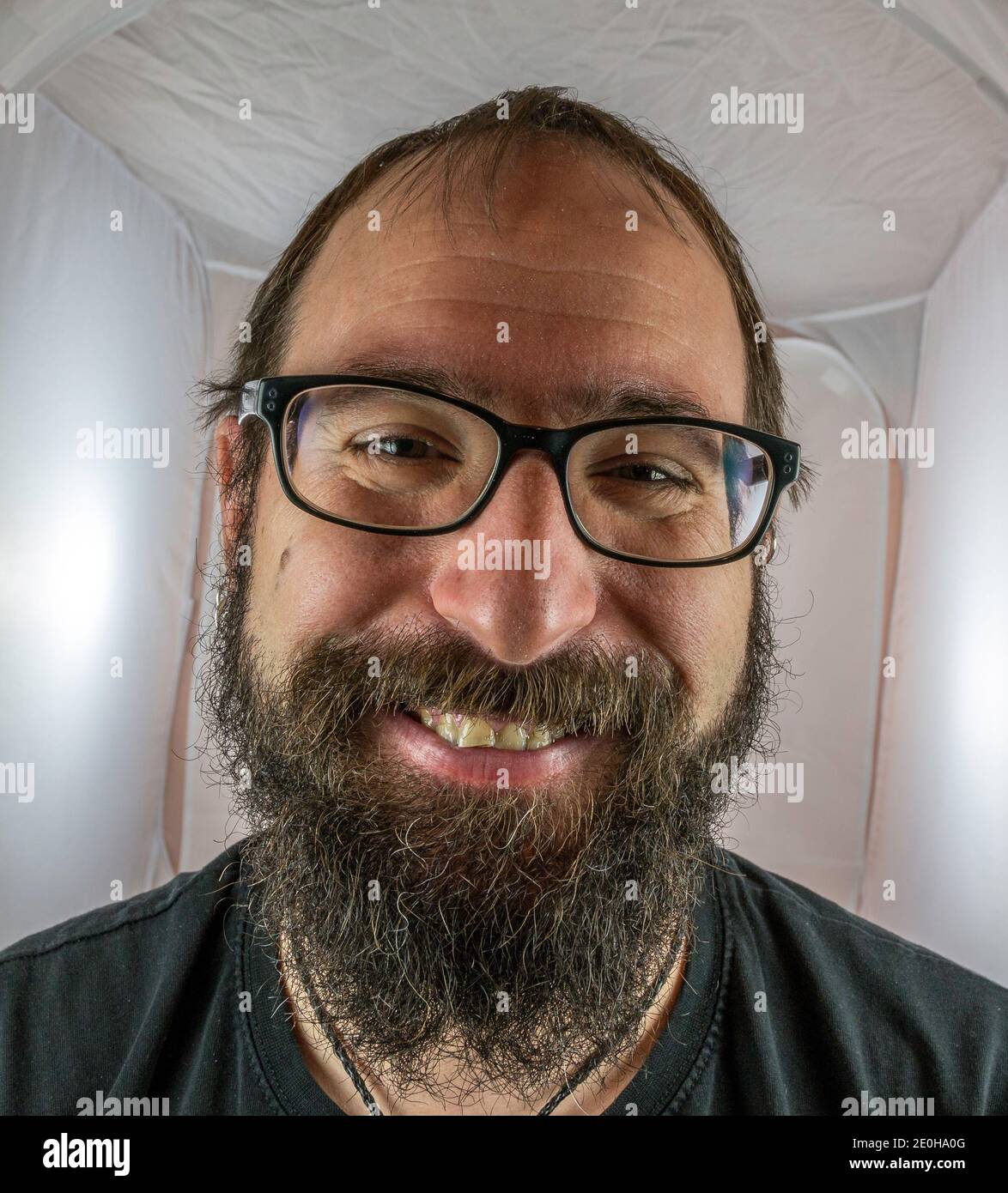 Ein bärtig lächelnder Mann in guter Stimmung mit Schwarz Brille Stockfoto