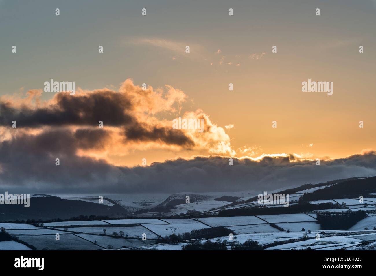 Der letzte Sonnenuntergang von 2020 über der verschneiten Landschaft von Mid-Wales, gesehen vom Offa's Dyke Fußweg in der Nähe von Knighton, Powys, UK am Silvesterabend, 2020 Stockfoto