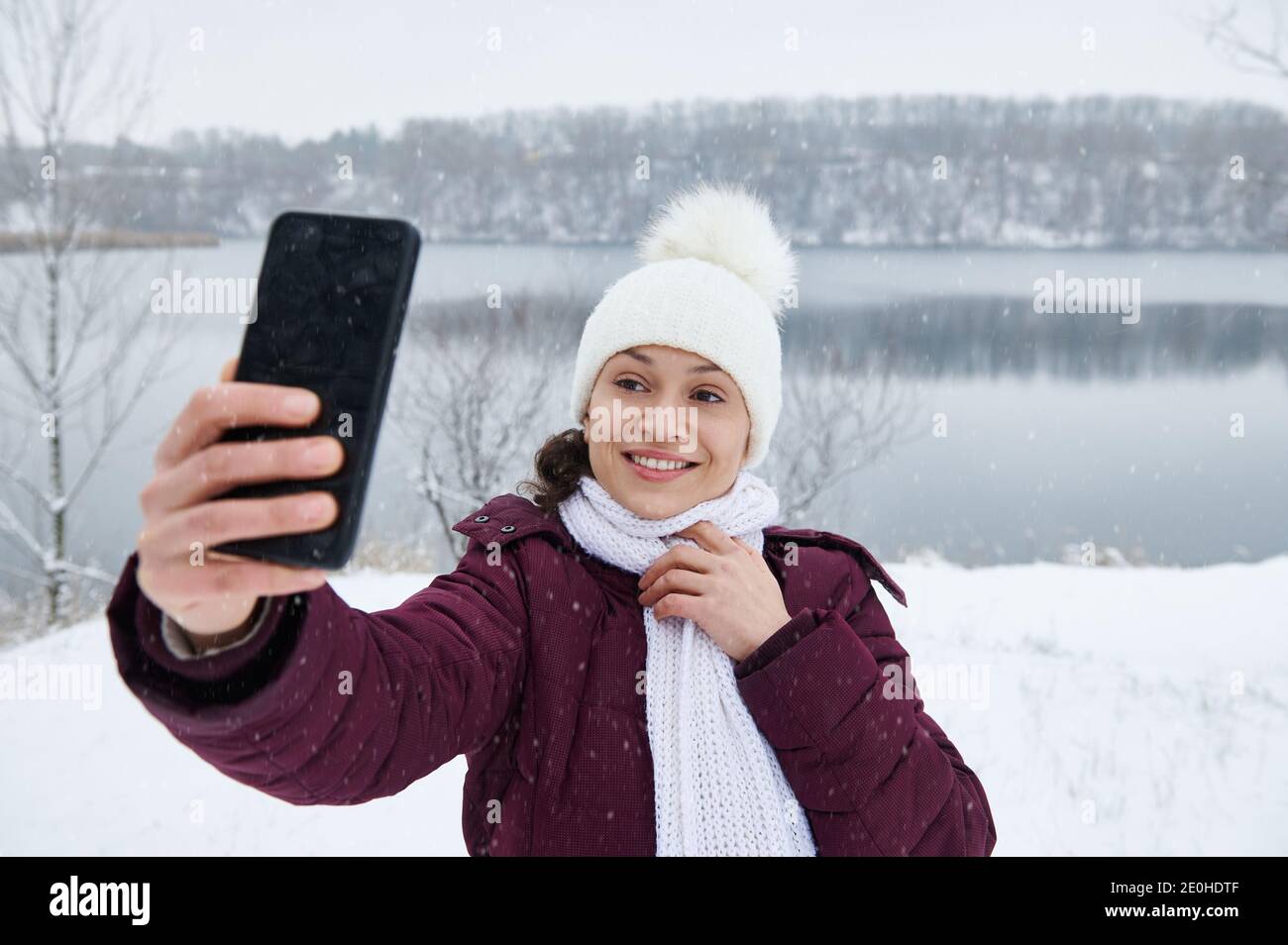 Eine schöne Brünette Frau macht ein Selfie auf dem Hintergrund Von schneebedeckten Landzunge Stockfoto