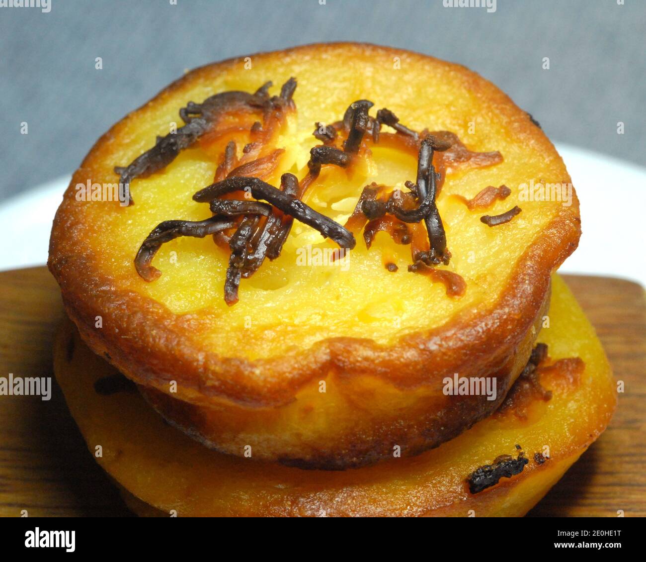 Nahaufnahme des philippinischen Dessert Reiskuchen mit geriebenem Käse auf der Oberseite. Schuss auf einen Holzspatel und Keramik-Untertasse. Stockfoto