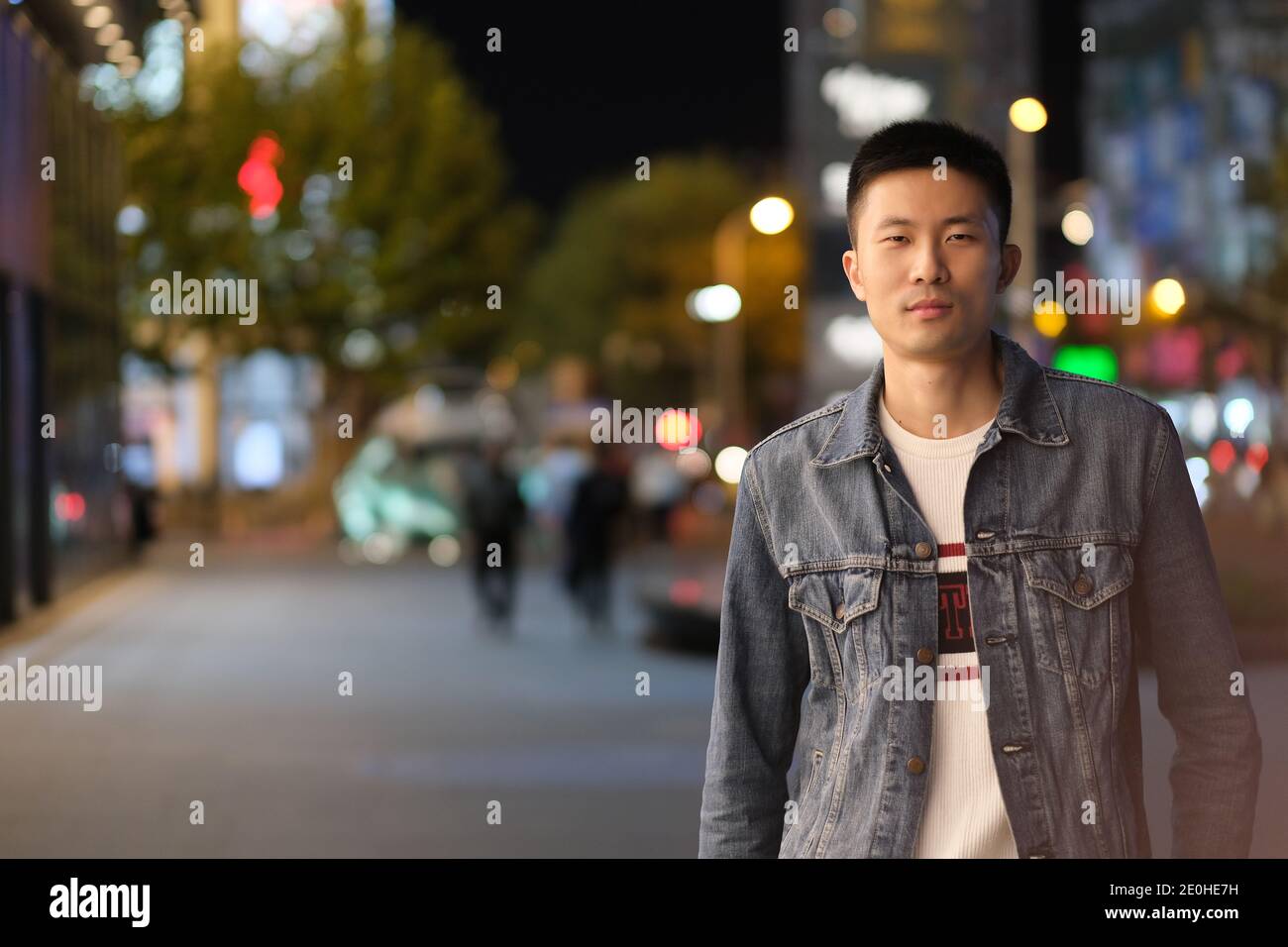 Mittelaufnahme eines asiatischen jungen Mannes in der modernen Stadt bei Nacht, Blick auf die Kamera Stockfoto