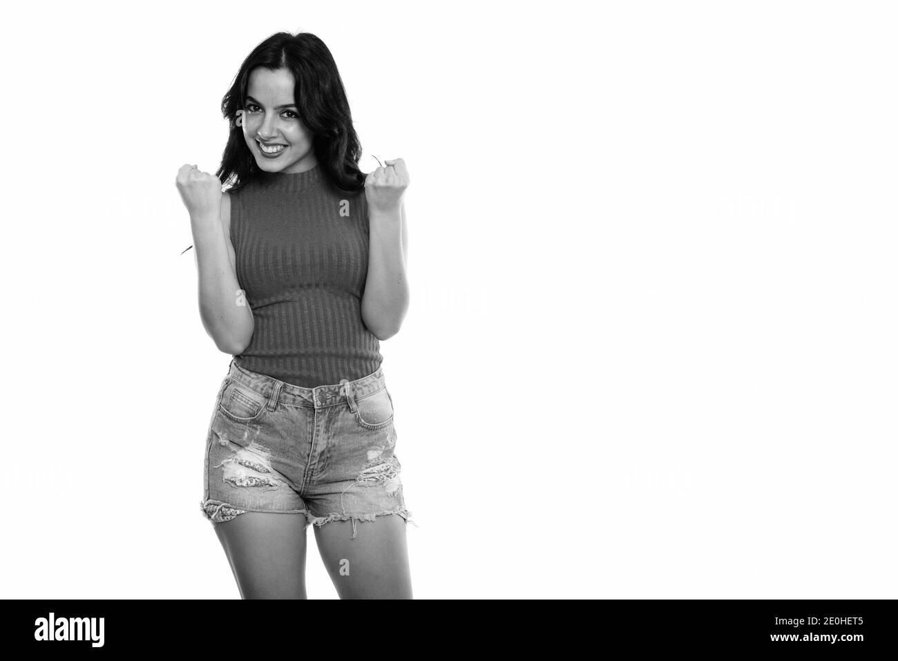 Studio shot der jungen spanischen Frau glücklich lächelnd und stehend, während sie aufgeregt Stockfoto