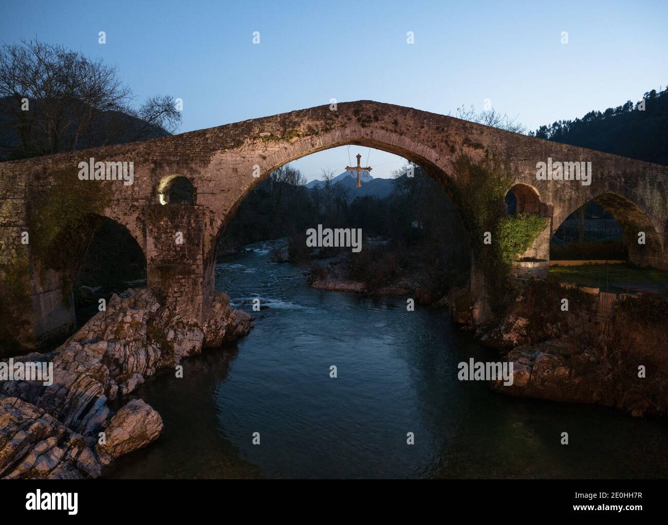 Beleuchtete mittelalterliche römische Buckelbrücke über den Fluss Sella In Cangas de Onis bei Sonnenuntergang blaue Stunde Oriente Asturien nördlich von Spa Stockfoto