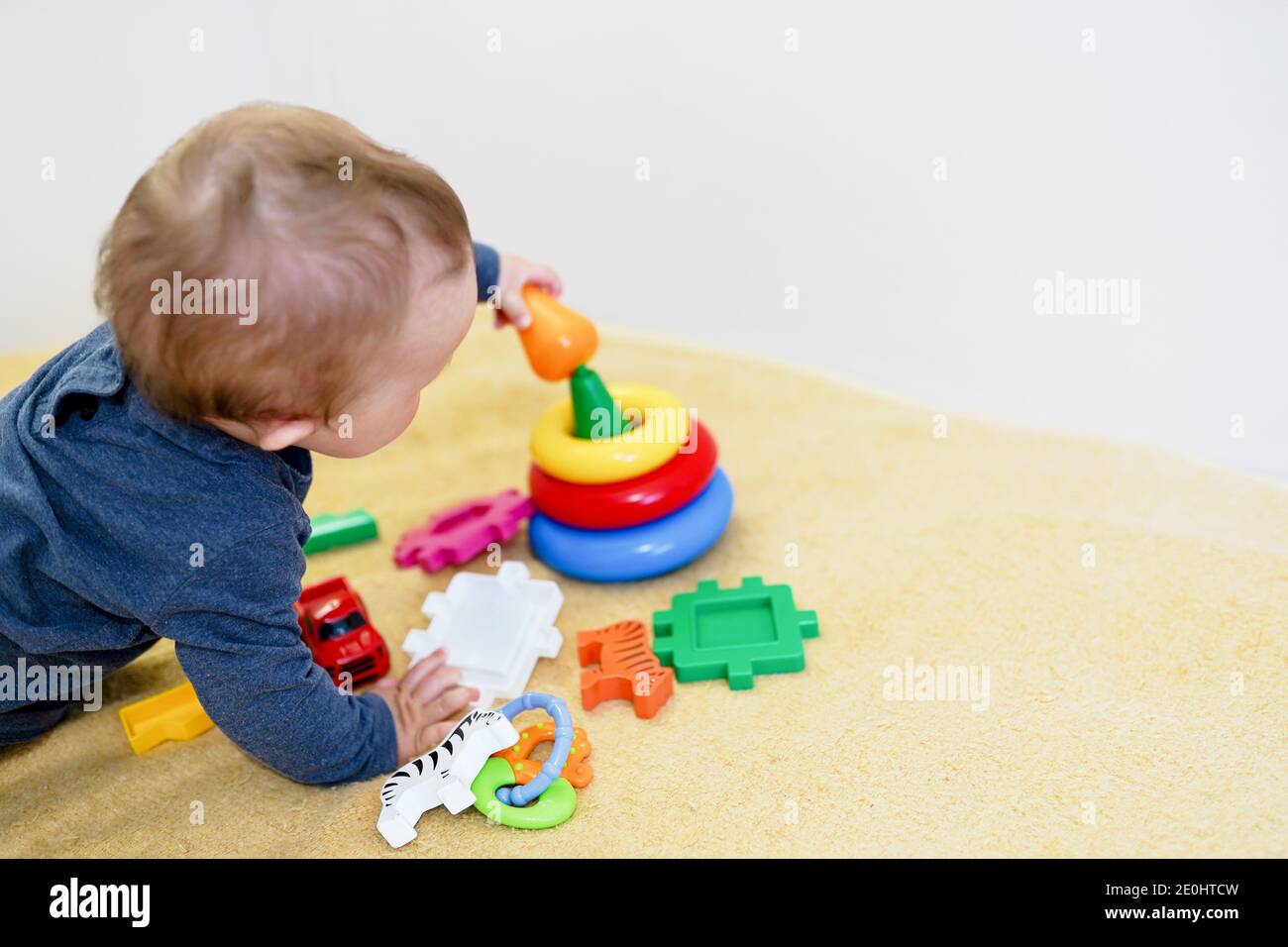 Baby smilling und spielen mit bunten Spielzeug zu Hause. Kind Hintergrund mit Kopieplatz. Frühe Entwicklung für Kinder. Stockfoto