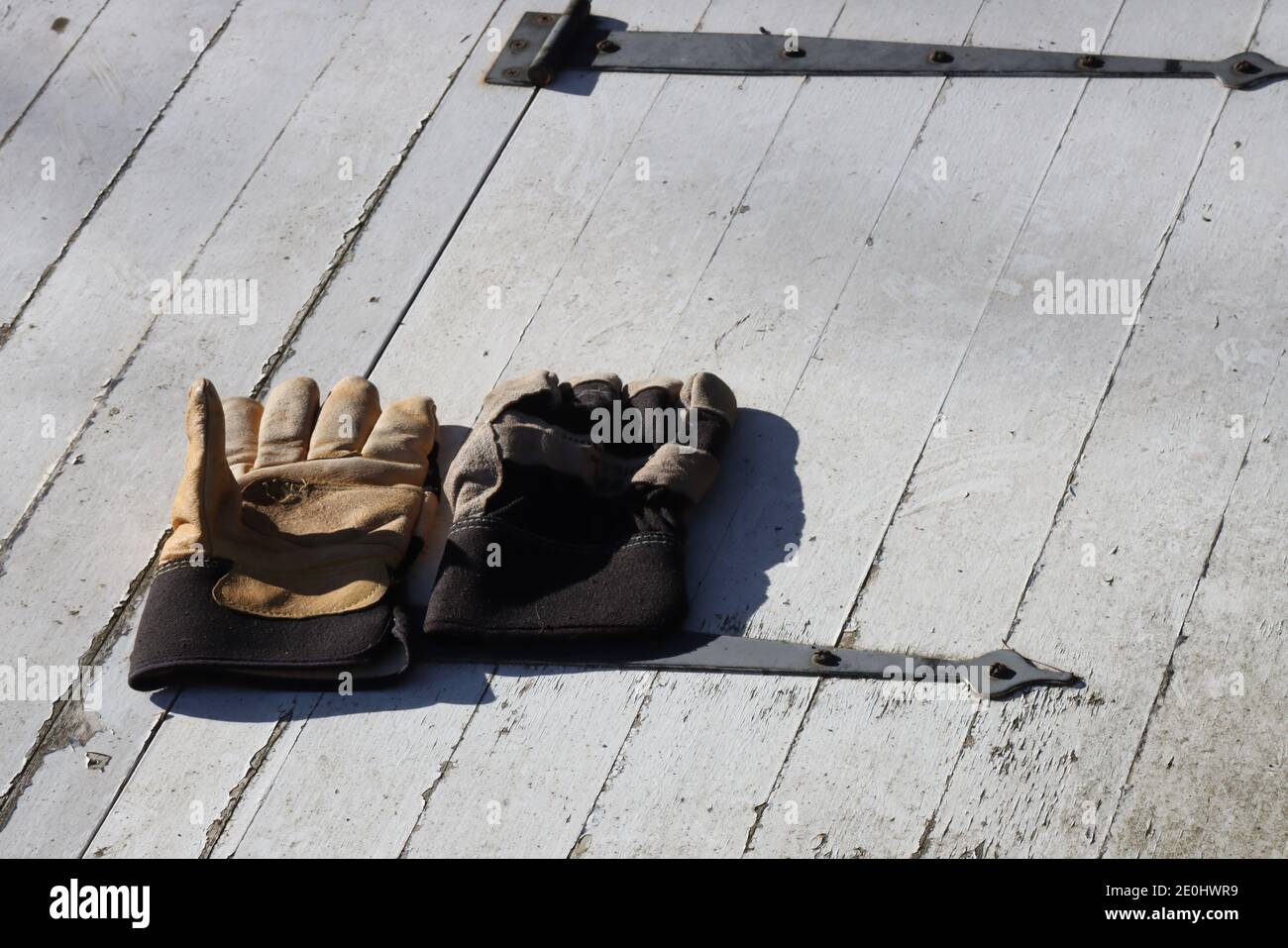 Die Arbeitshandschuhe befinden sich an der alten Kellertür. Stockfoto