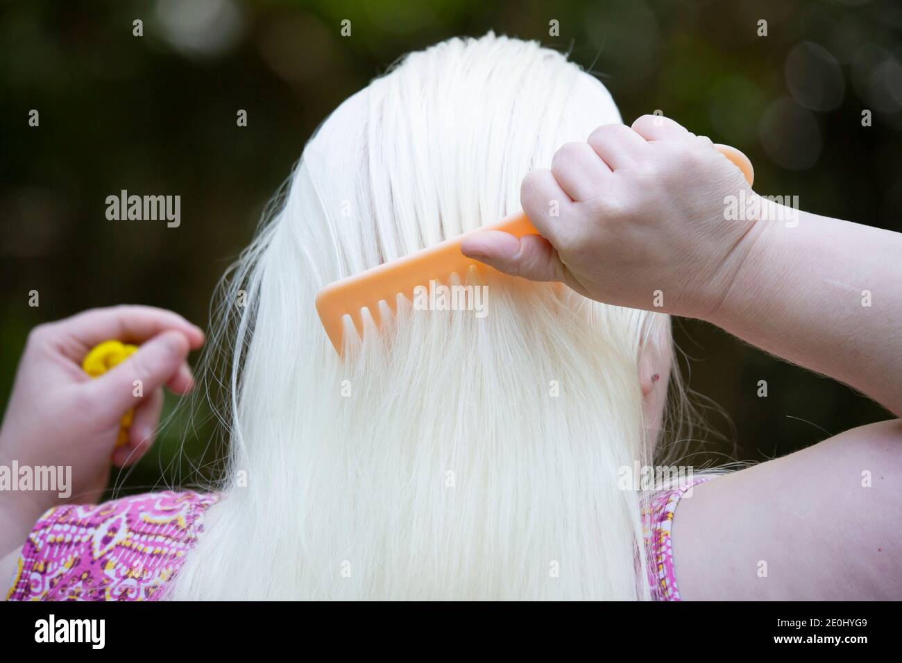 Frau kämmt lange, weiße Haare vor dem Styling im Freien Stockfoto
