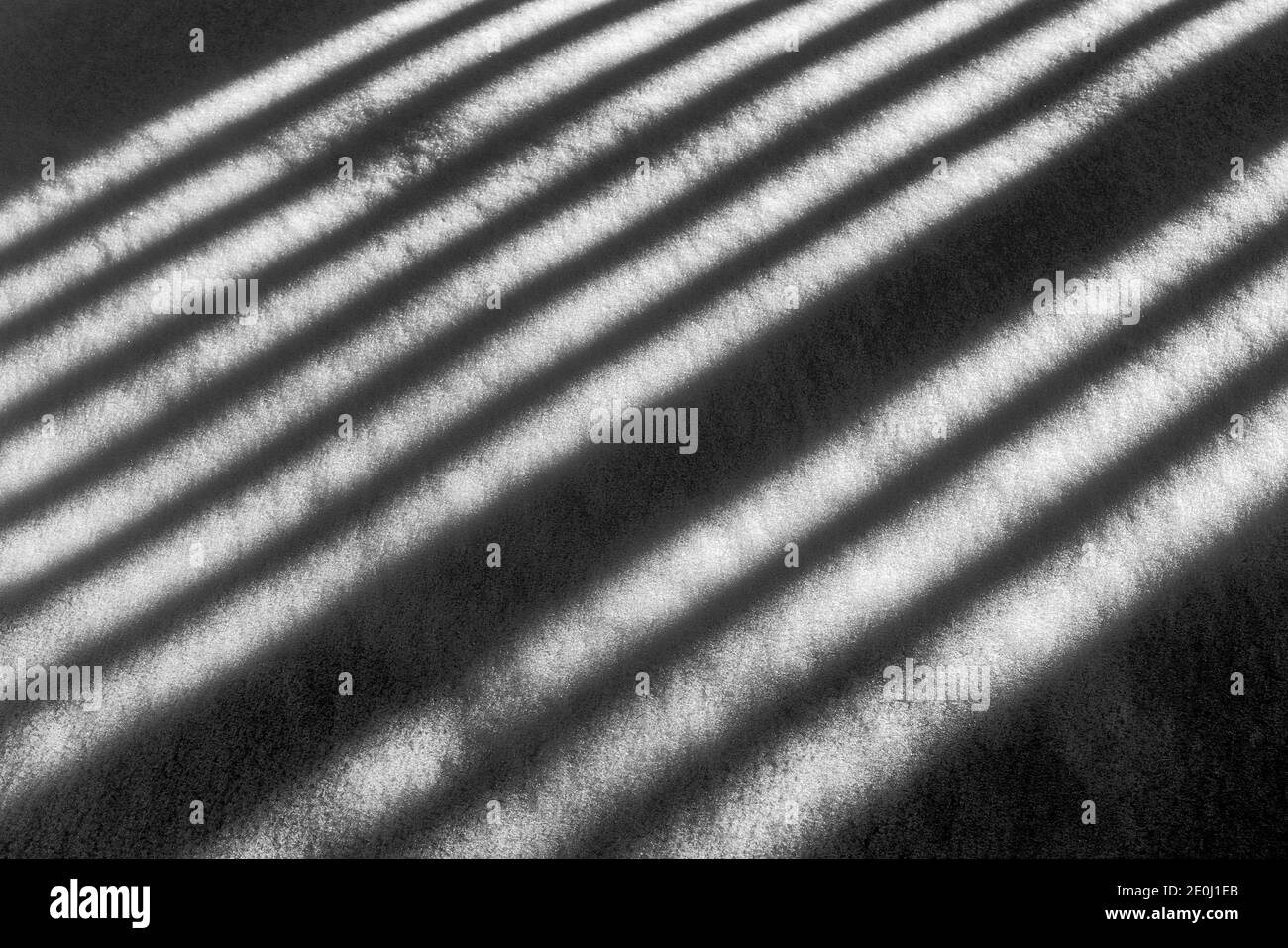 Schwarz-Weiß-Ansicht der weißen Vinyl-Pfostenzaun wirft lange Winter Schatten auf Neuschnee; Salida; Colorado; USA Stockfoto