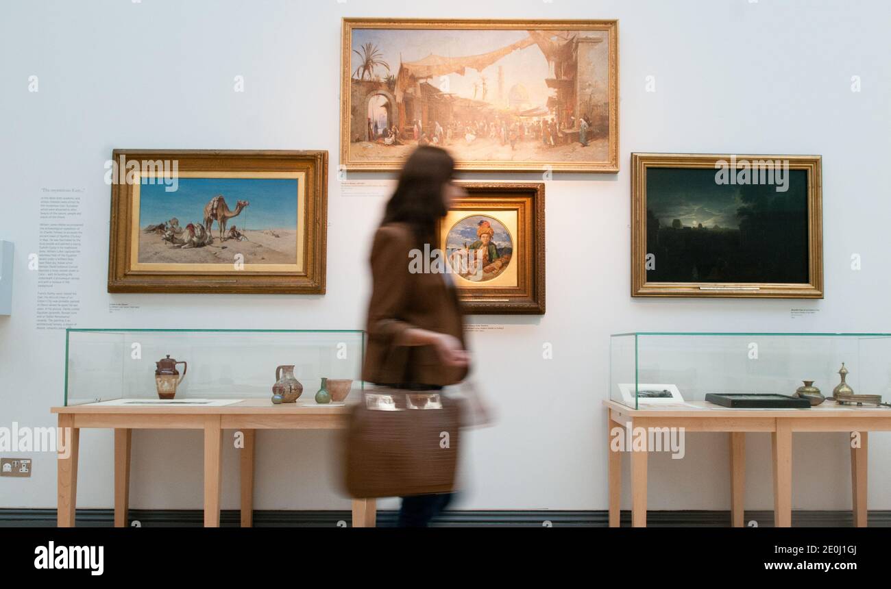 Allein weiße junge Frau, die in einer Kunstgalerie an Ölgemälden vorbeigeht, ist verschwommen und zeigt Bewegungen, während sie ihren Kopf dreht, um die Kunstwerke anzusehen Stockfoto
