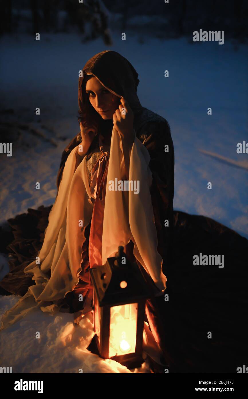 Fantasy Nacht Aufnahme der jungen Frau sitzen mit Vintage Laterne Blick auf Sie. Mittelalterliches Märchenkonzept Stockfoto