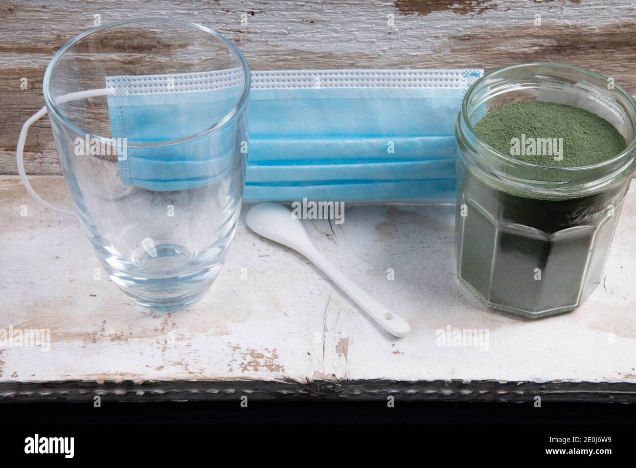 Mundschutz mit Glaslöffel und grünem Superfood-Pulver Stockfoto