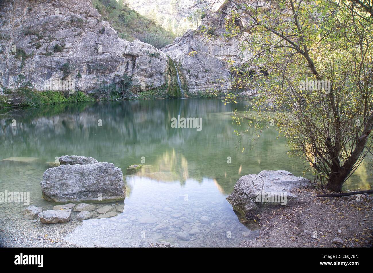 Ein Wasserfall stürzt in einen großen Pool mit klarem Wasser In spanien Stockfoto