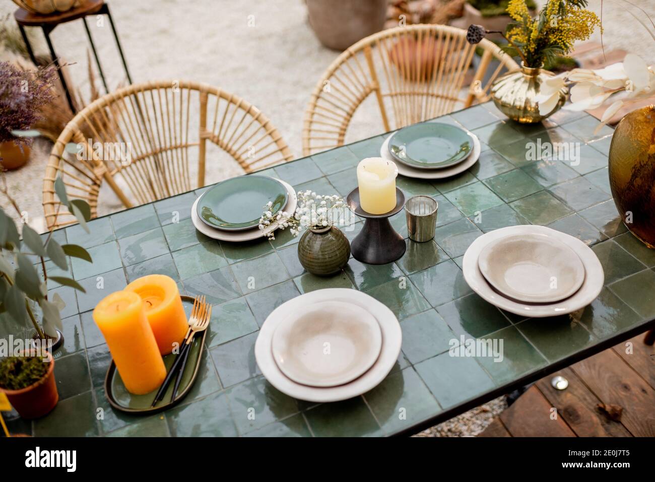 Festlich dekoriertes Tischtuch in Grüntönen mit Kerzen, Kräutern und Blumen im natürlichen Boho-Stil im Freien Stockfoto