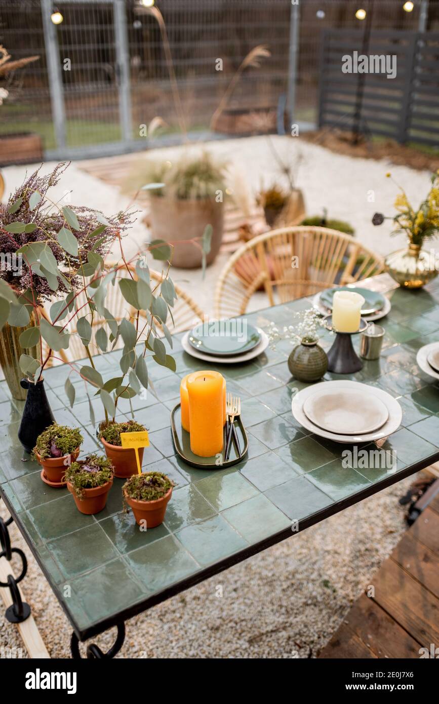 Festlich dekoriertes Tischtuch in Grüntönen mit Kerzen, Kräutern und Blumen im natürlichen Boho-Stil im Freien Stockfoto