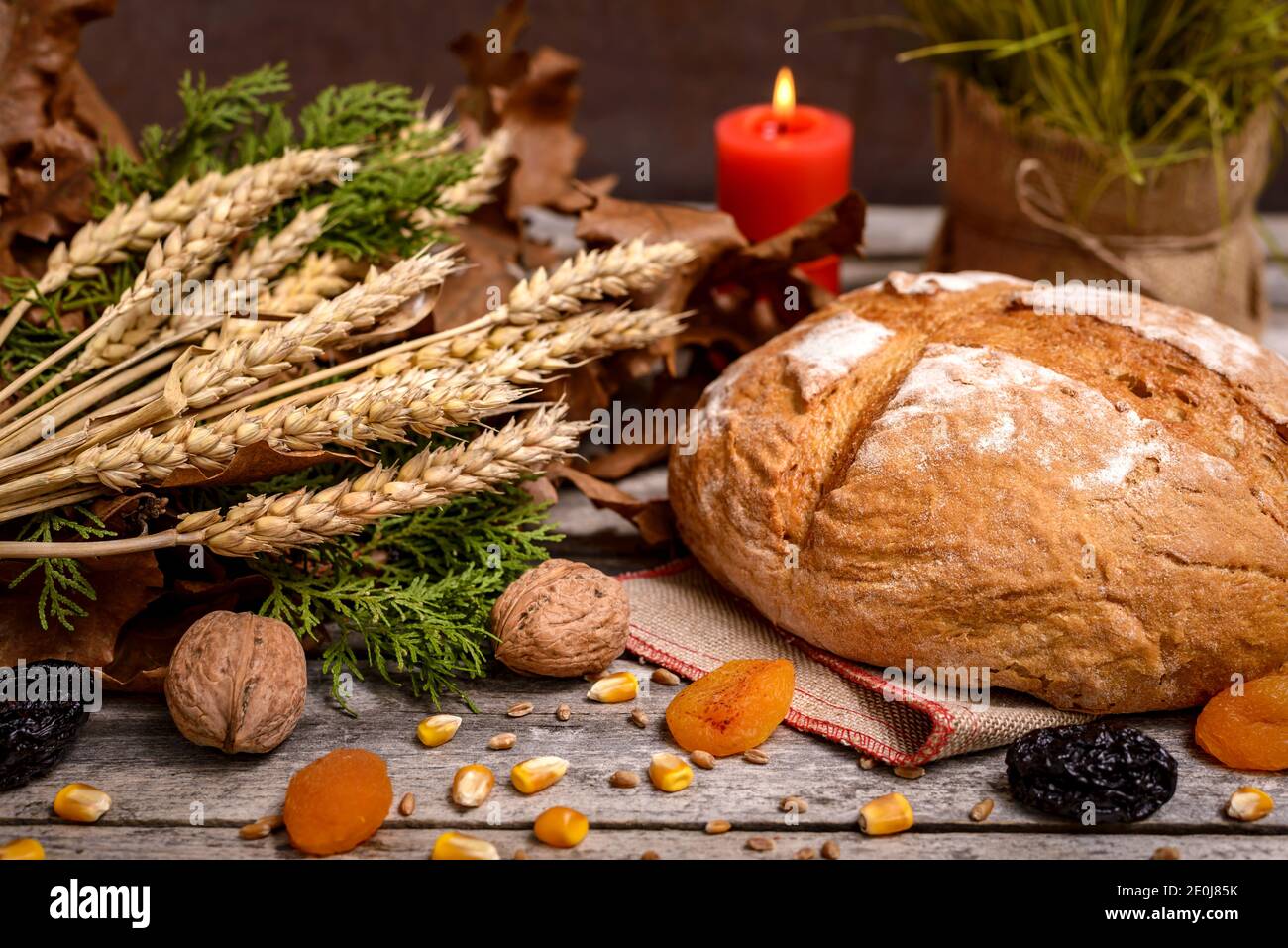 Traditionelles Essen für orthodoxen Heiligabend. Yule log oder badnjak, Brot, Getreide, getrocknete Früchte und brennende Kerze auf Holztisch. Konzept-Feier Stockfoto