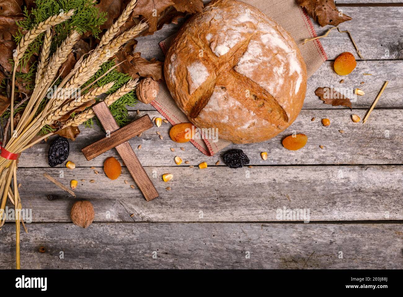 Traditionelles Essen für orthodoxen Heiligabend. Yule log oder badnjak, Brot, Getreide, getrocknete Früchte und Holzkreuz auf Holztisch. Konzept Feier o Stockfoto