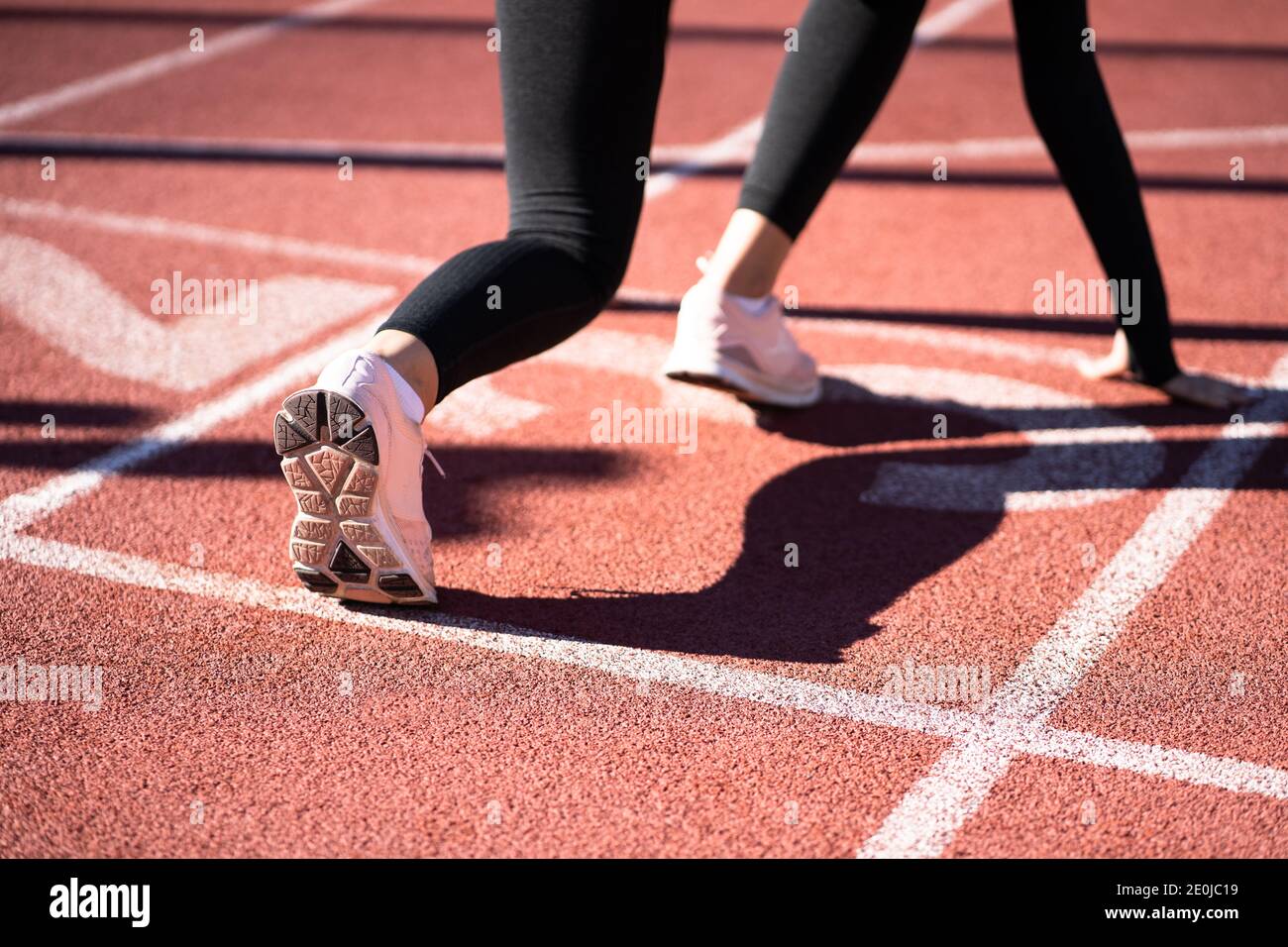 Rückansicht einer Joggingfrau auf der Laufstrecke, die sich auf den Start vorbereitet. Stockfoto