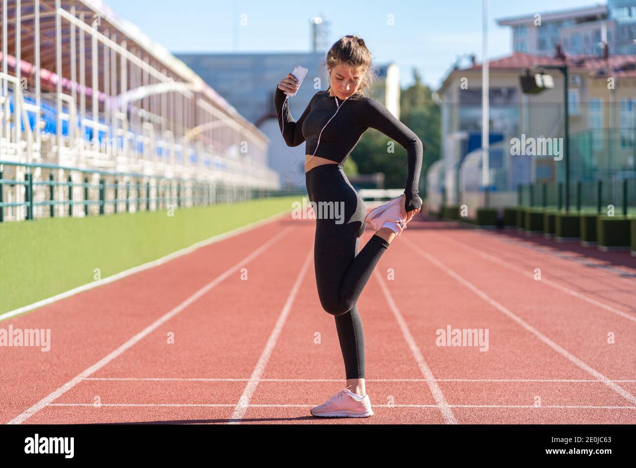 Fit Frau Stretching Muskeln machen funktionelles Training, dabei Übungen für die Beine, Oberschenkelmuskulatur dehnen vor dem Joggen, auf einem Laufband Gummi st Stockfoto