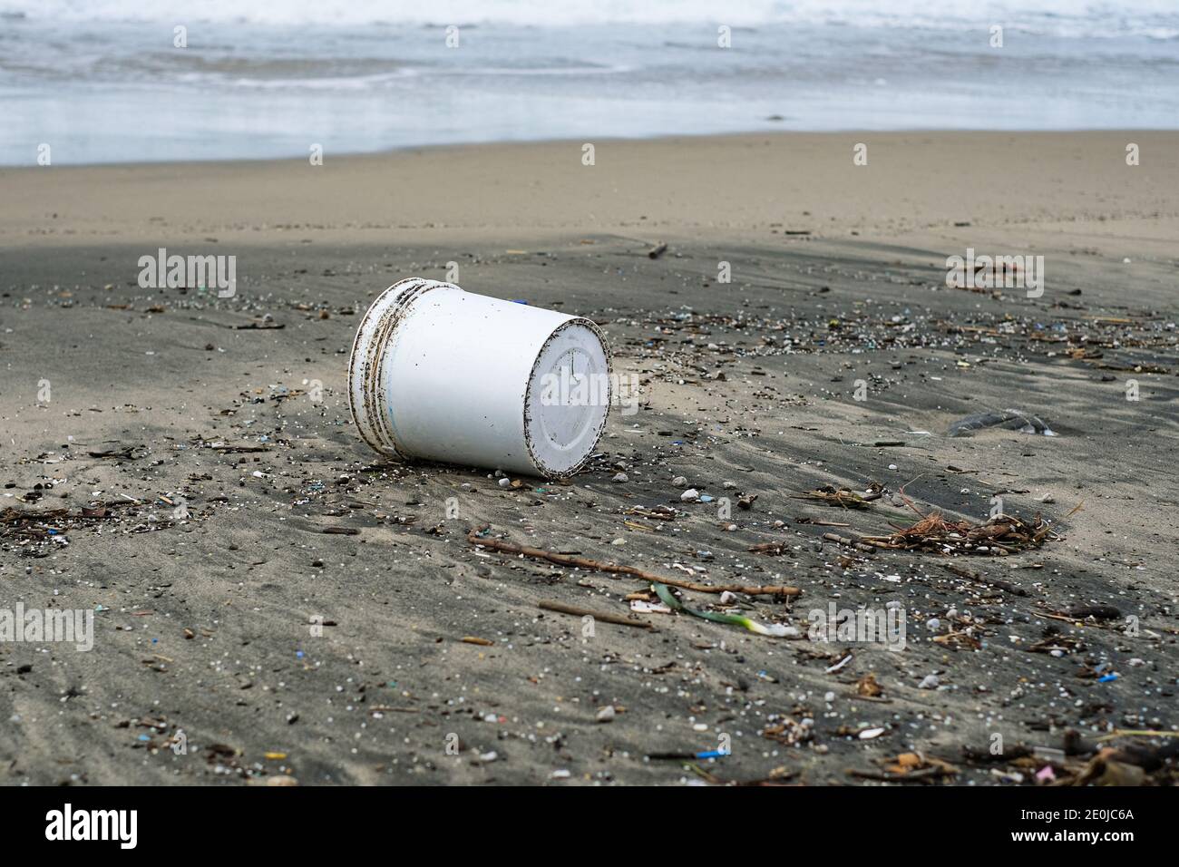 Plastikbehälter Abfall und Teerverschmutzung an stürmischer Küste, Umwelt Verunreinigung von Abfällen Stockfoto