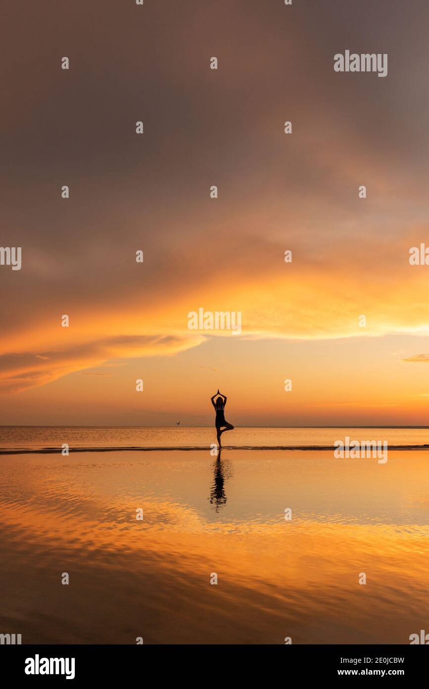 Meditation Frau praktiziert Baum Yoga Pose am Strand bei Sonnenuntergang. Speicherplatz kopieren. Stockfoto