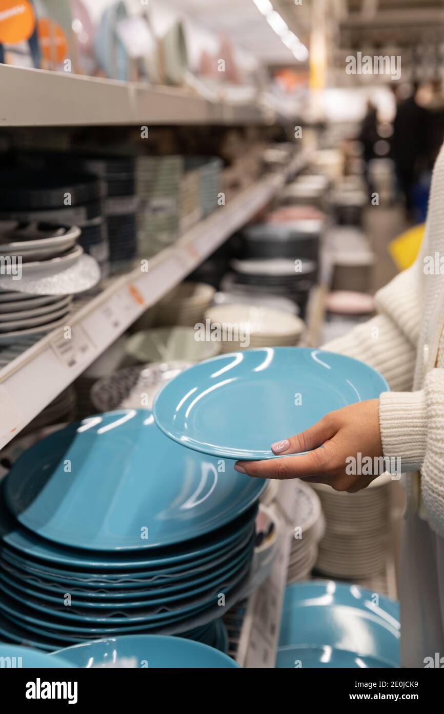 Frau Kunde Auswahl und Kauf blauen Ton Geschirr Teller, Abendessen Utensil für ihre Küche im Haushaltswarenladen oder Supermarkt. Einkaufskonzept. Stockfoto