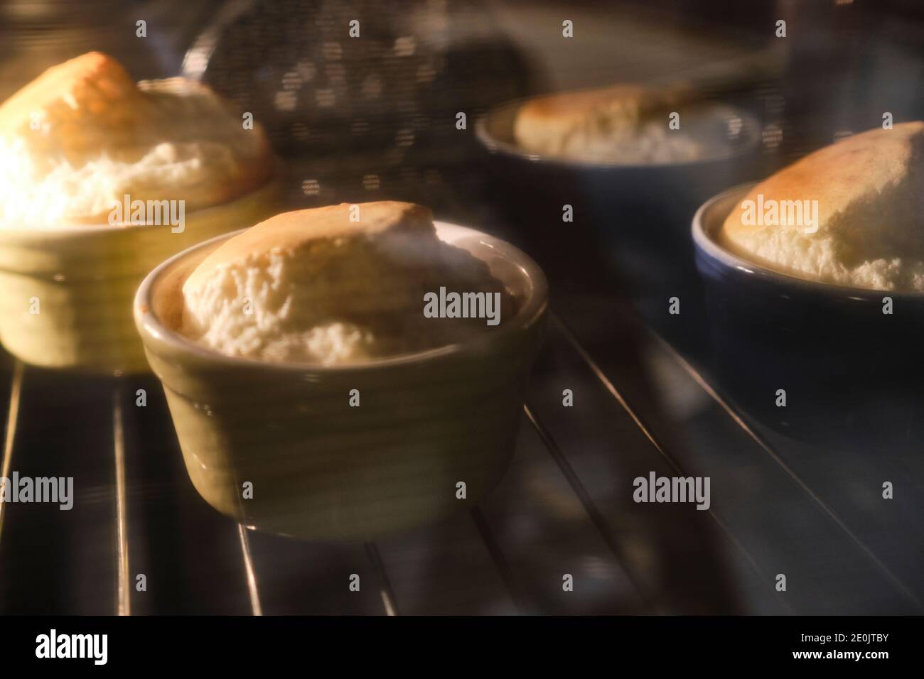 Vier hausgemachte Gorgonzola Soufflés, durch das Glas des Heizofens gesehen. Gorgonzola ist ein typischer Blauschimmelkäse aus Norditalien. Stockfoto