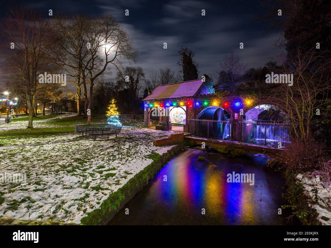 Kidderminster, Großbritannien. Januar 2021. UK Wetter: Alles ist ruhig, da dieser verschneite Neujahrstag zu Ende geht. Eine kalte und trockene Nacht wird für Worcestershire mit Temperaturen unter Null vorhergesagt, bis in die frühen Morgenstunden. Hübsche Weihnachtslichter leuchten hell, ihre bunte Reflexion sichtbar unter einem mondbeleuchteten Himmel in diesem lokalen Park. Kredit: Lee Hudson/Alamy Live Nachrichten Stockfoto