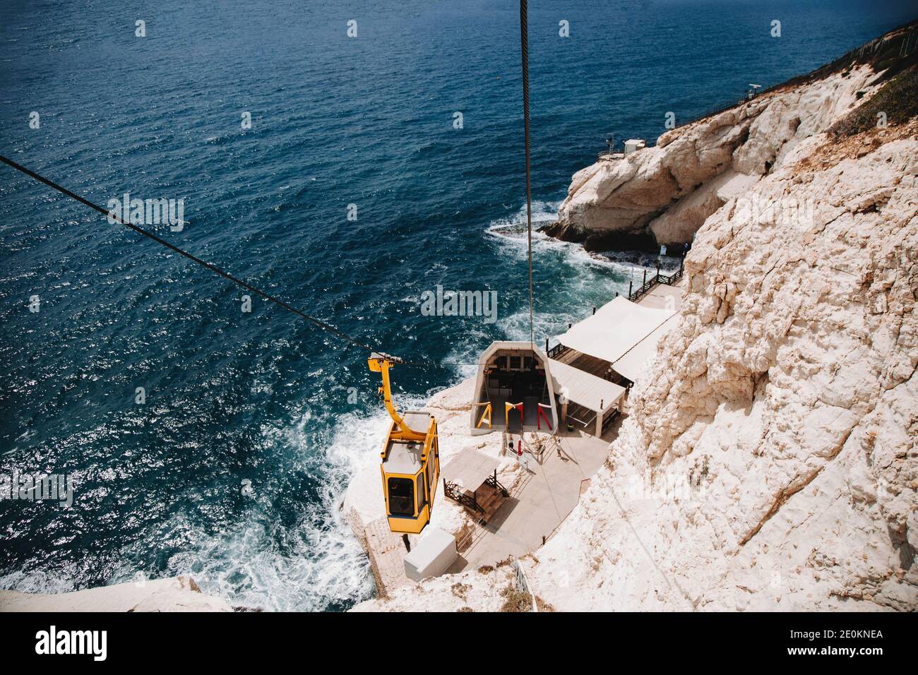 Gelbe Seilbahn steigt auf dem Hintergrund des Meeres, Steine, Felsen und Berge. Pfad zu Rosh Hanikra Grotten Stockfoto
