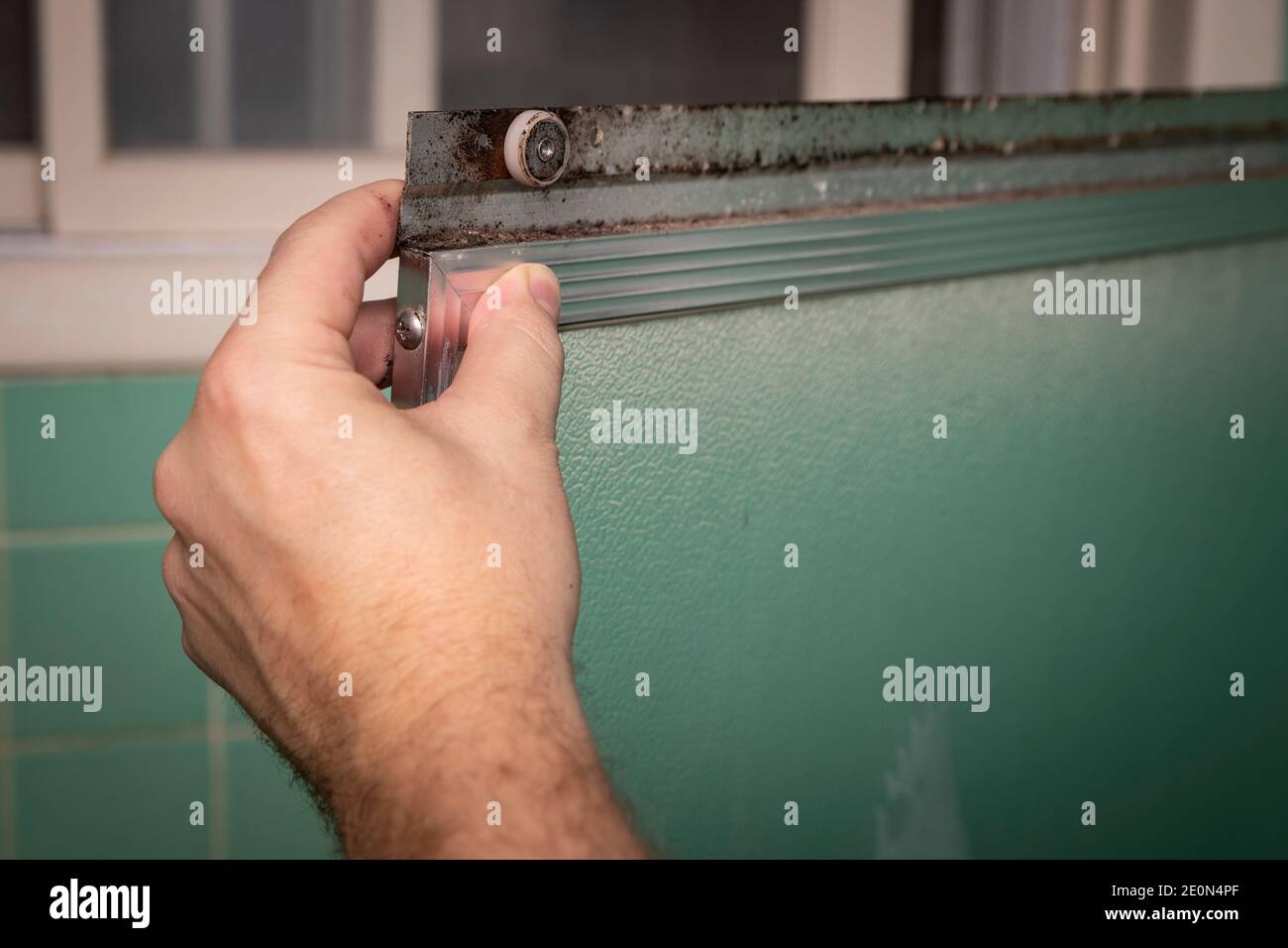 Hand hält schmutzige Schiebeduschtür Rahmen, in Retro-farbigen und Stil Hause Badezimmer Einstellung. Stockfoto
