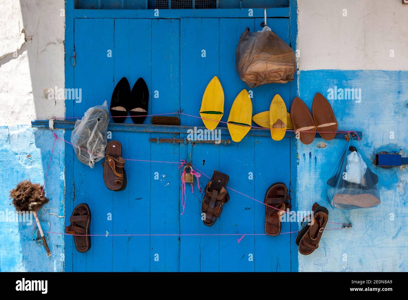 Verschiedene Schuhe hängen an einer blauen Tür in Kasbah des Oudaias in Rabat in Marokko. Der Vorort ist berühmt für seine blau-weißen Gebäude. Stockfoto