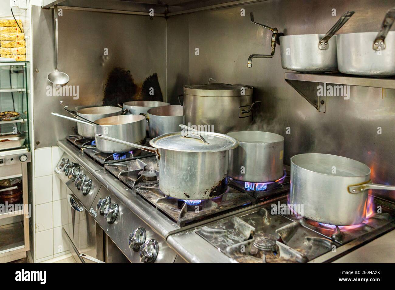 Verschiedene Töpfe kochen auf einem Herd in einer Industrieküche In Italien Stockfoto