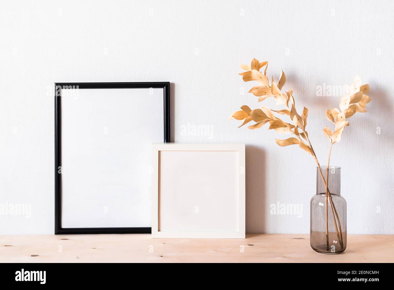 Getrocknete Blumen und ein Fotodramen rammen gegen eine helle Wand hinein Ein minimalistischer Stil Stockfoto