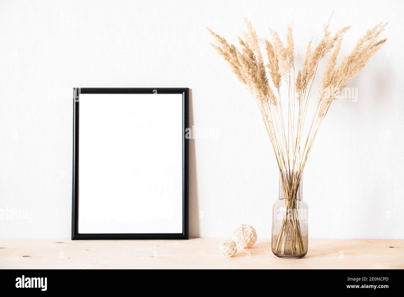 Getrocknete Blumen und ein photoframe gegen eine helle Wand Ein minimalistischer Stil Stockfoto