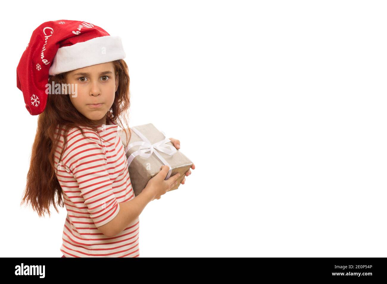 Kleine schöne Mädchen in Weihnachtsmann Hut hält ihr Geschenk Gierig Blick auf die Kamera aggressiv isoliert Copyspace egoistischen Kindern Kinderschmil Stockfoto