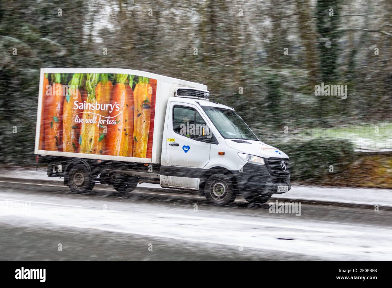 Ein Sainsbury Lieferwagen macht seinen Weg durch fallenden Schnee, Großbritannien Stockfoto