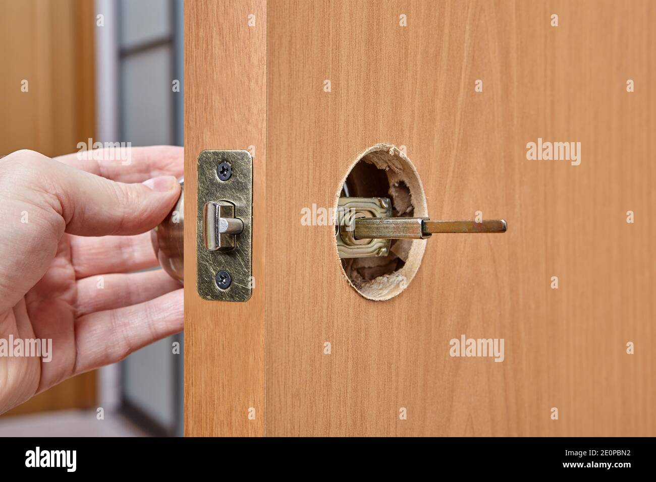 Der Installateur schiebt die Spindel des Türgriffs durch die Öffnung in der Verriegelungseinheit und der Planbohrung. Stockfoto