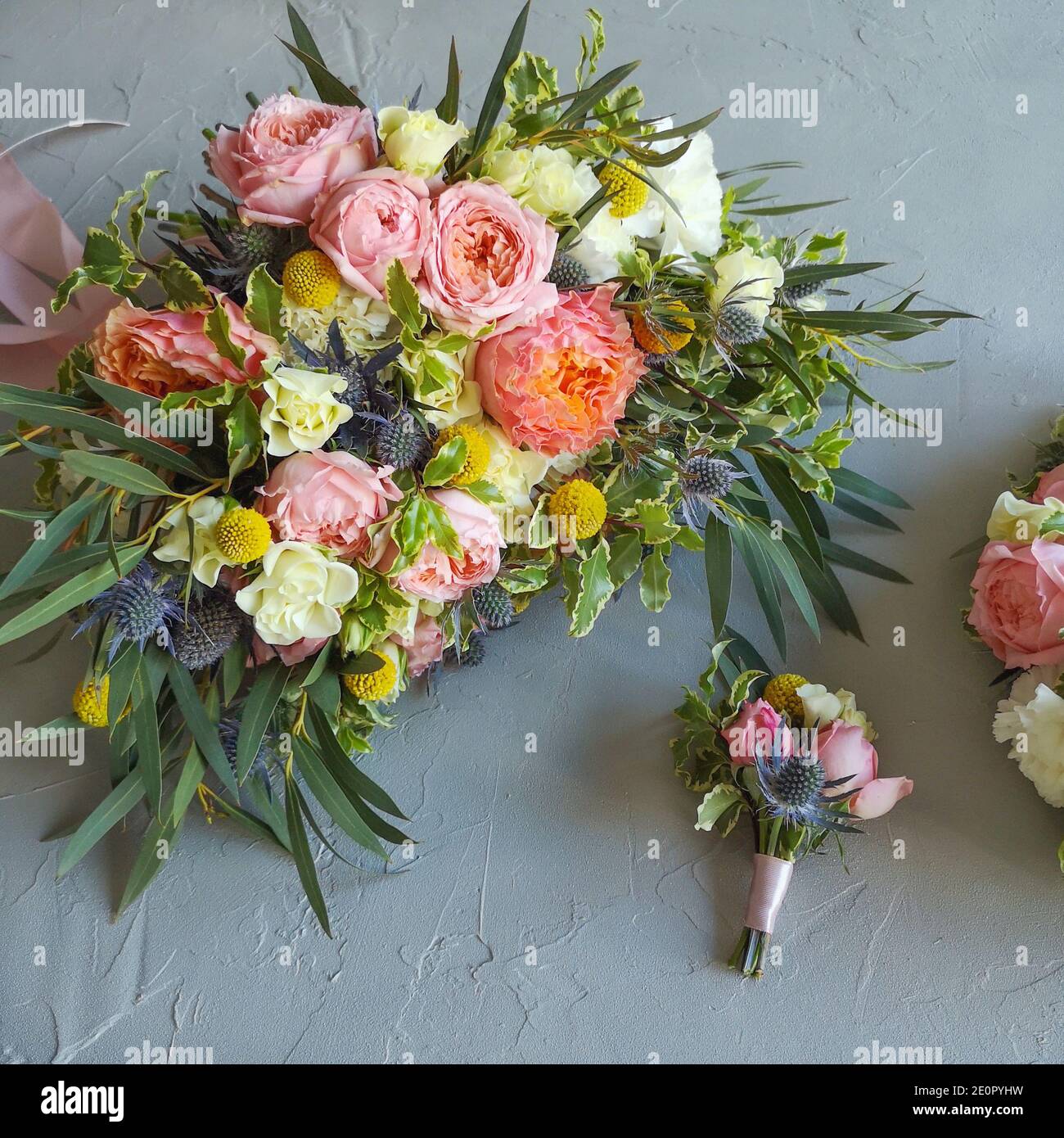 brautstrauß und Boutonniere stehen auf dem Tisch. Der Bund besteht aus Rosen, Craspedia, Dianthus, Eringium und hellgrün. Online-Floristik-Training Stockfoto