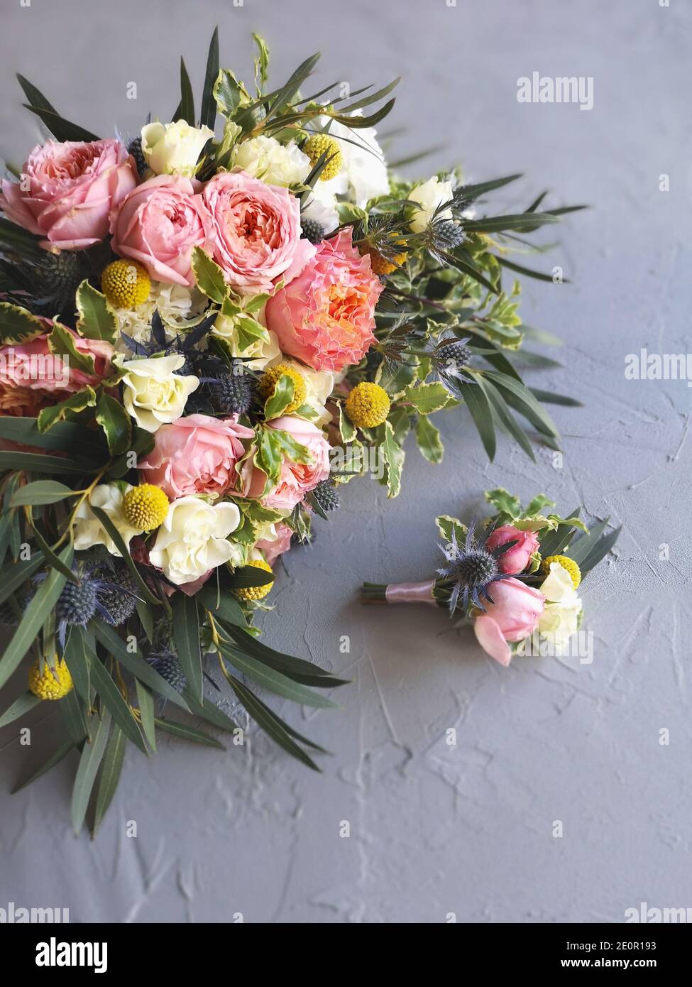 Brautstrauß aus rosa, weißen und gelben Blumen und Boutonniere des Bräutigams auf grauem Floristentisch. Draufsicht, Flachschlitze. Englische Garten Spray Rosen Stockfoto