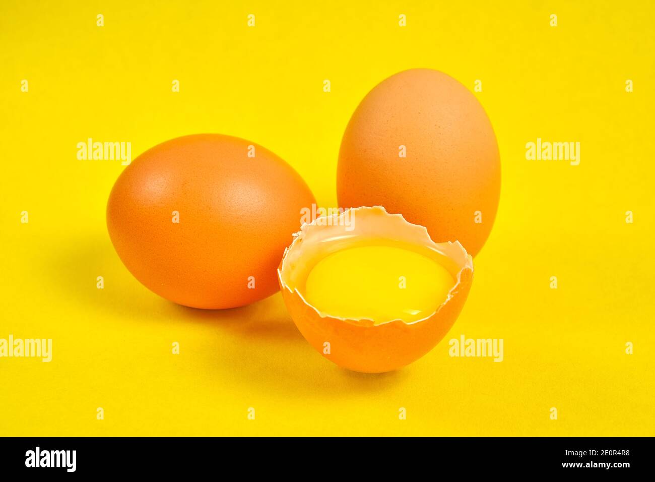 Hühnereier auf gelbem Hintergrund mit Eigelb gebrochen Stockfoto