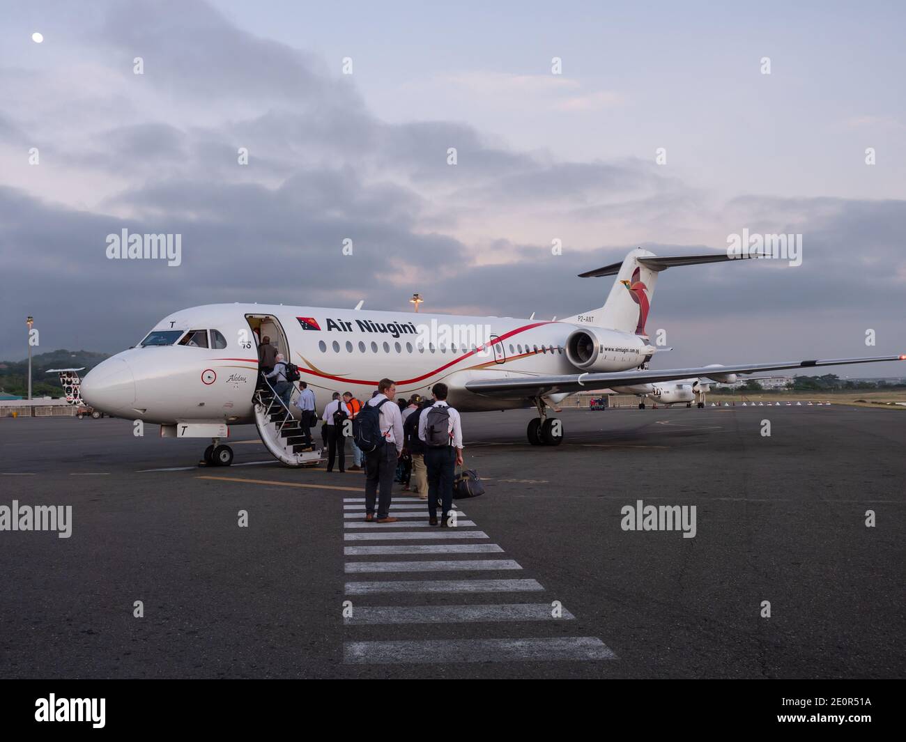 Passagiere, die einen Fokker 70 von Air Niugini am frühen Morgen am Jacksons International Airport in Port Moresby, der Hauptstadt von Papua-Neuguinea, besteigen. Stockfoto