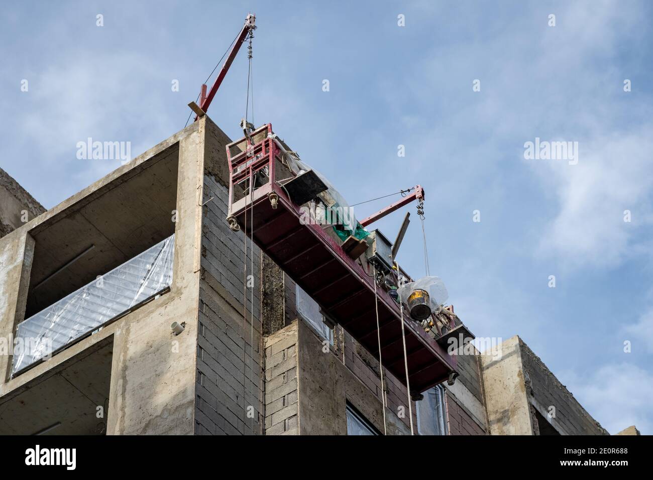 Bau Wiege an der Wand eines Hauses im Bau hängen. Arbeiter arbeiten am Bau Stockfoto