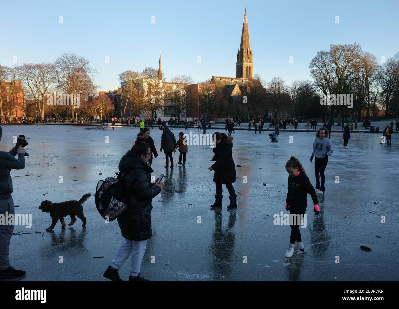 Glasgow, Großbritannien, 2. Januar 2021. Die Leute nutzen das kalte Wetter zum Schlittschuhlaufen und spazieren auf dem gefrorenen Bootsteich im Queen's Park, in der Südseite der Stadt. Die Polizei entfernte schließlich alle aus dem Eis, weil sie sich Sorgen um die Sicherheit gemacht hatte. Foto: Jeremy Sutton-Hibbert/ Alamy Live News Stockfoto