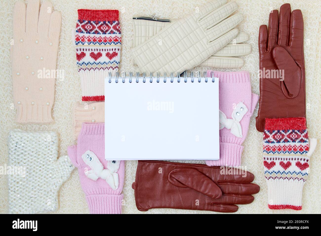 Winter flach Lay mit Fäustlingen, Handschuhen und Notizbuch auf weißem gestricktem Hintergrund. Stockfoto