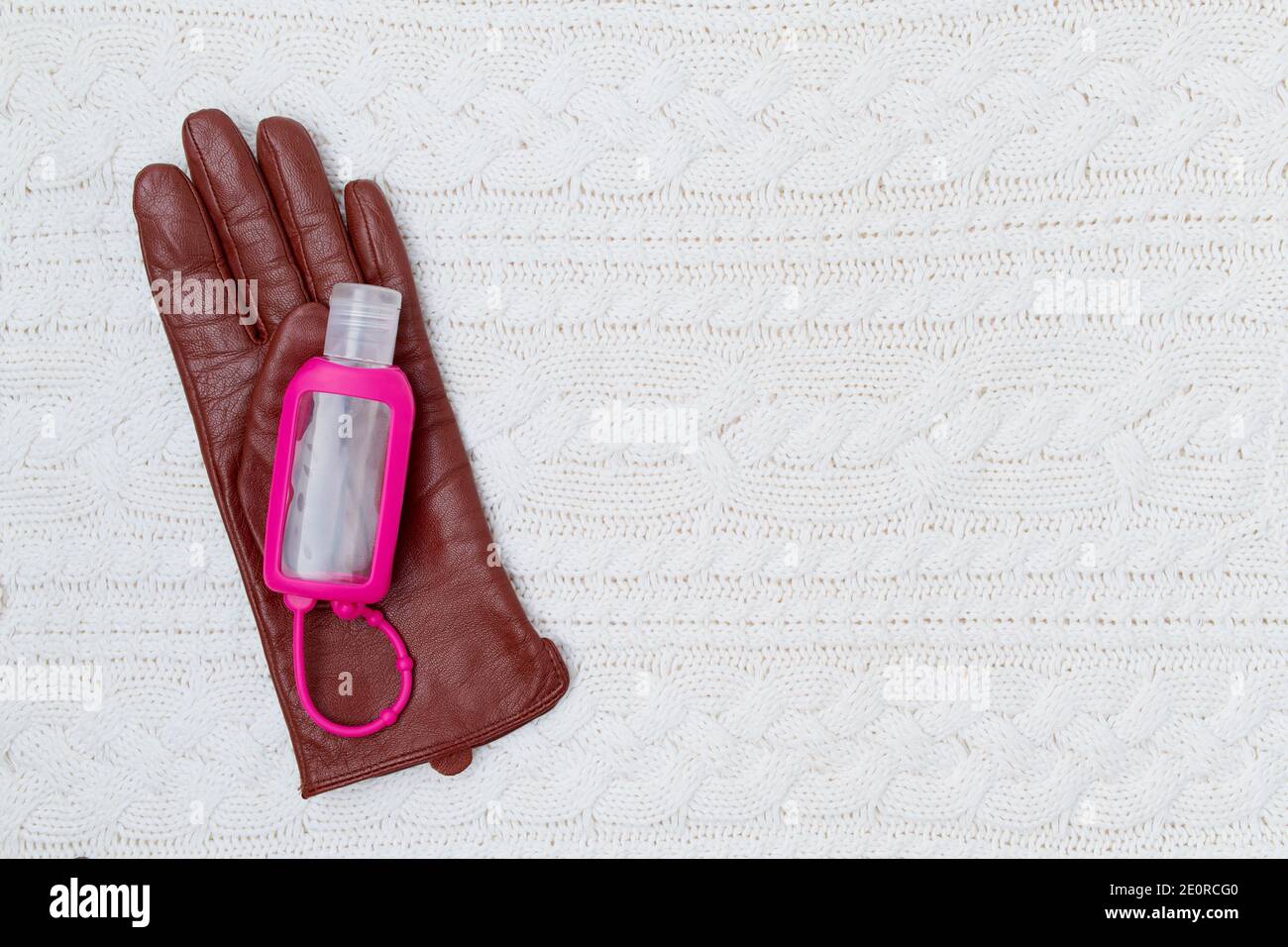 Winter flach legen mit Handschuhen und Desinfektionsmittel auf weißem gestrickten Hintergrund. Stockfoto