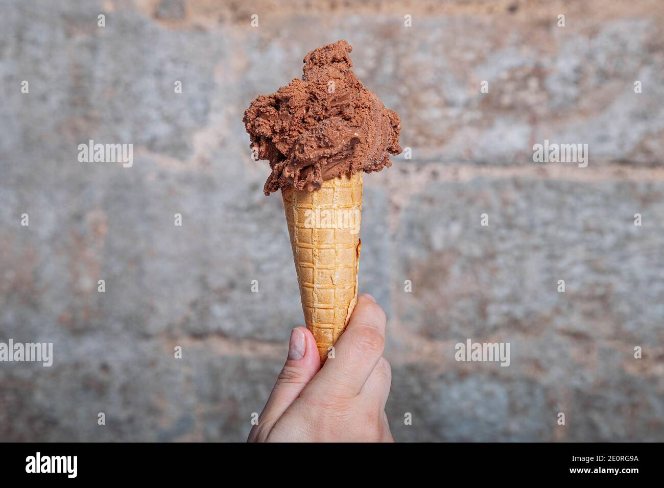 Hand halten Schokolade Eis Kegel. Schokoladeneis in Waffelkegel Stockfoto