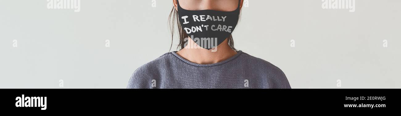 Anti-Maske-Nachricht Ich WIRKLICH NICHT KÜMMERN Text auf Gesichtsbedeckung als stummer Protest Banner Panorama geschrieben. Nicht erkennbare Frau trägt Gesichtsmasken Stockfoto