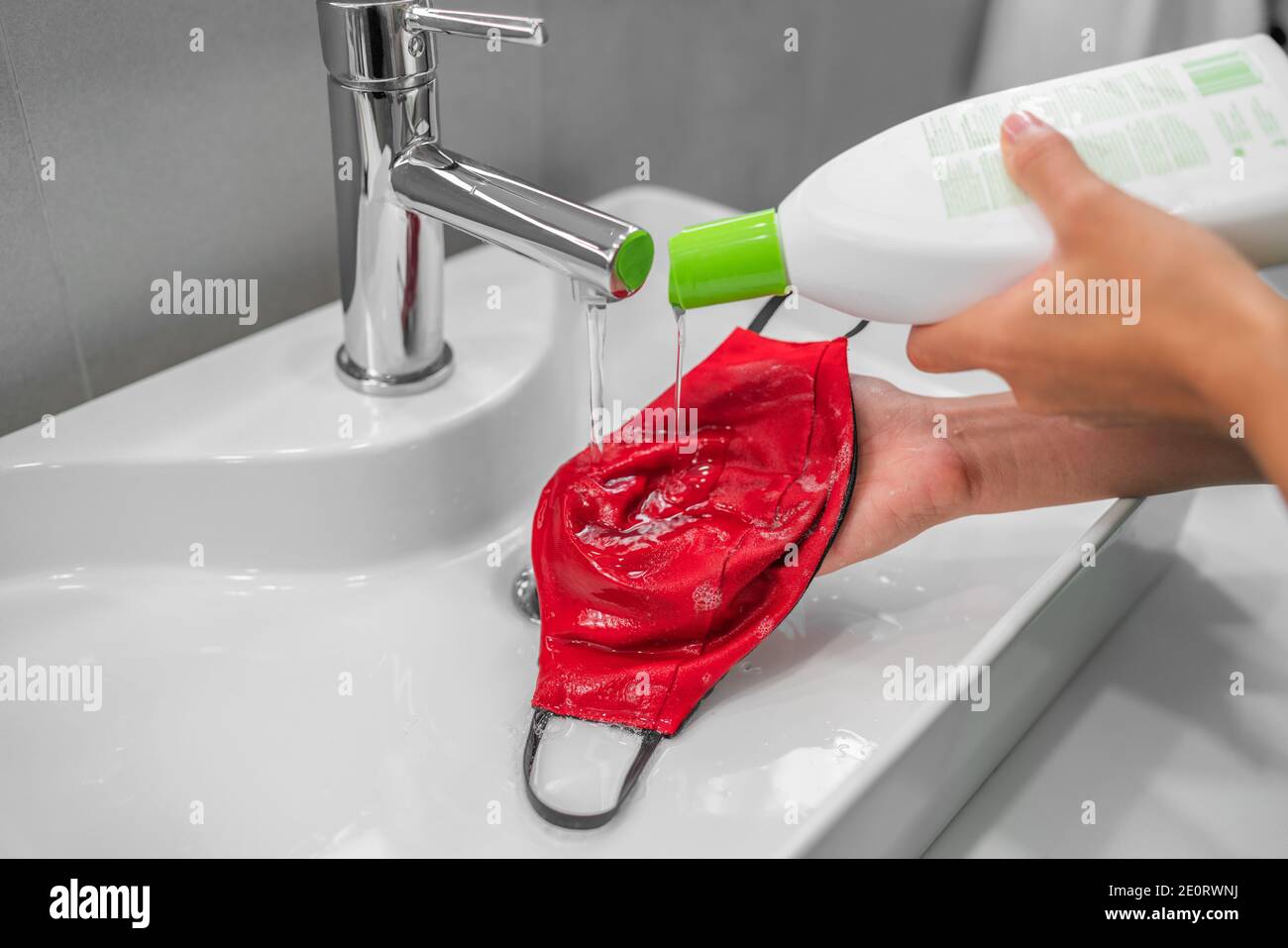 Wasch Gesichtsmaske zu Hause Waschbecken mit flüssigen Waschseife von Hand. Wiederverwendbare Stoffmasken müssen gereinigt werden Stockfoto