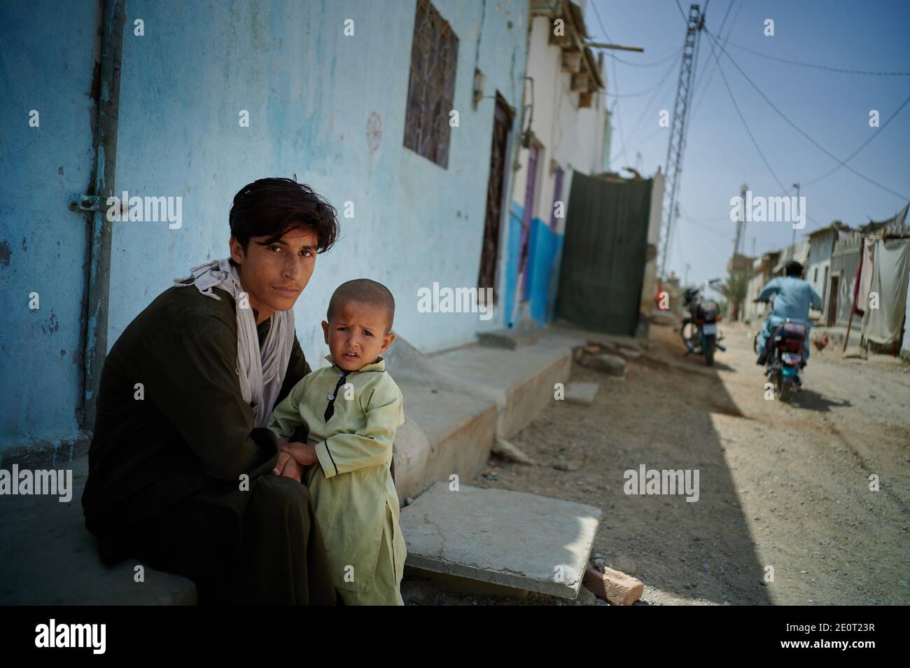 Während der Coronavirus-Pandemie sitzt Ahsan, 18 Jahre alt, vor seinem Haus mit seinem jüngeren Bruder Aziz, 4 Jahre alt, in Mohammad Colony in Baldia Town, Karachi, der wichtigsten Hafenstadt Pakistans. Stockfoto