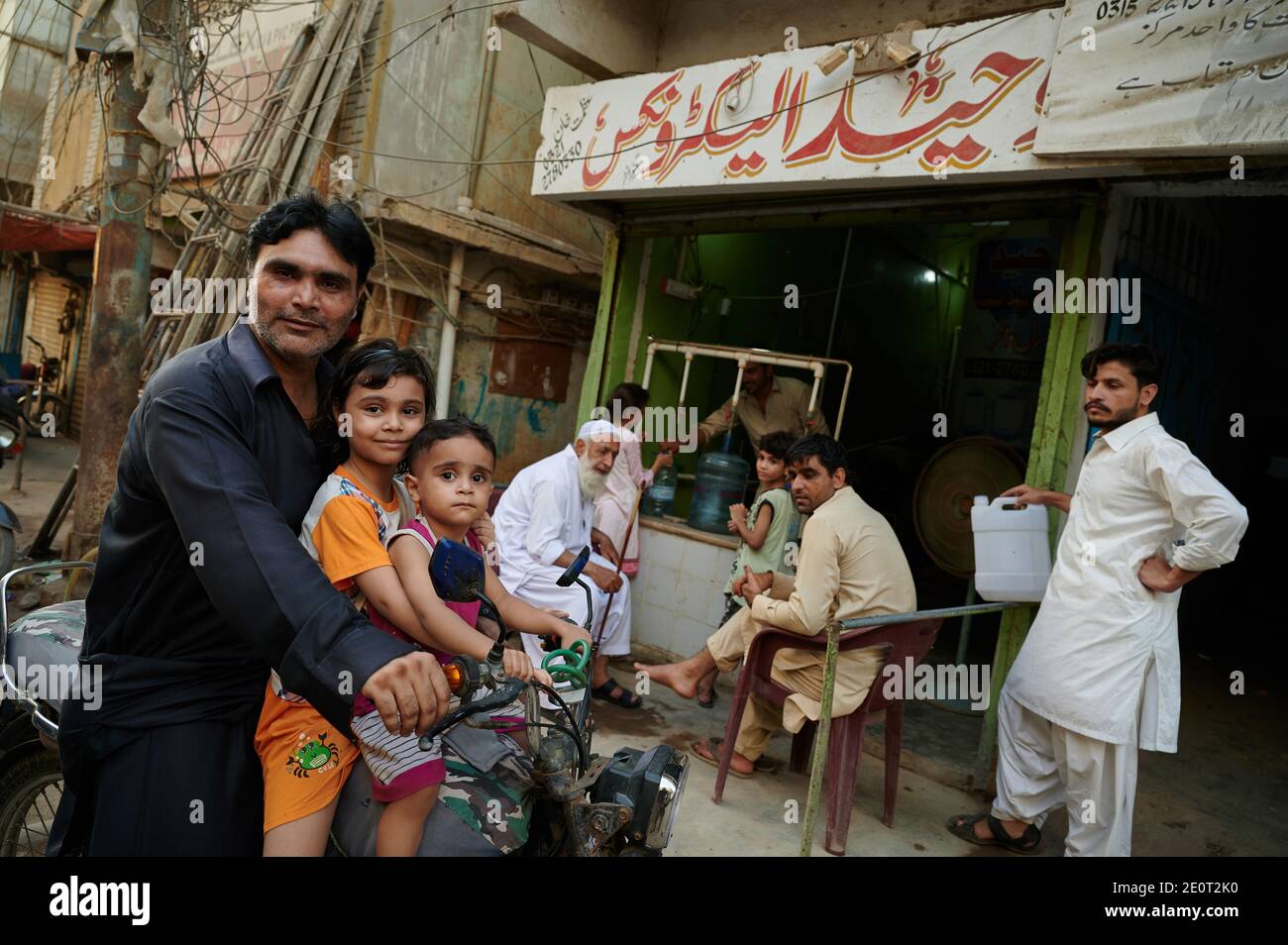 Inmitten der Coronavirus-Pandemie, die im Land rasch ansteigt, sitzt ein Mann mit seinen Kindern auf seinem Motorrad vor einem Geschäft im Kimari-Viertel in Karachi, der wichtigsten Hafenstadt Pakistans. Stockfoto