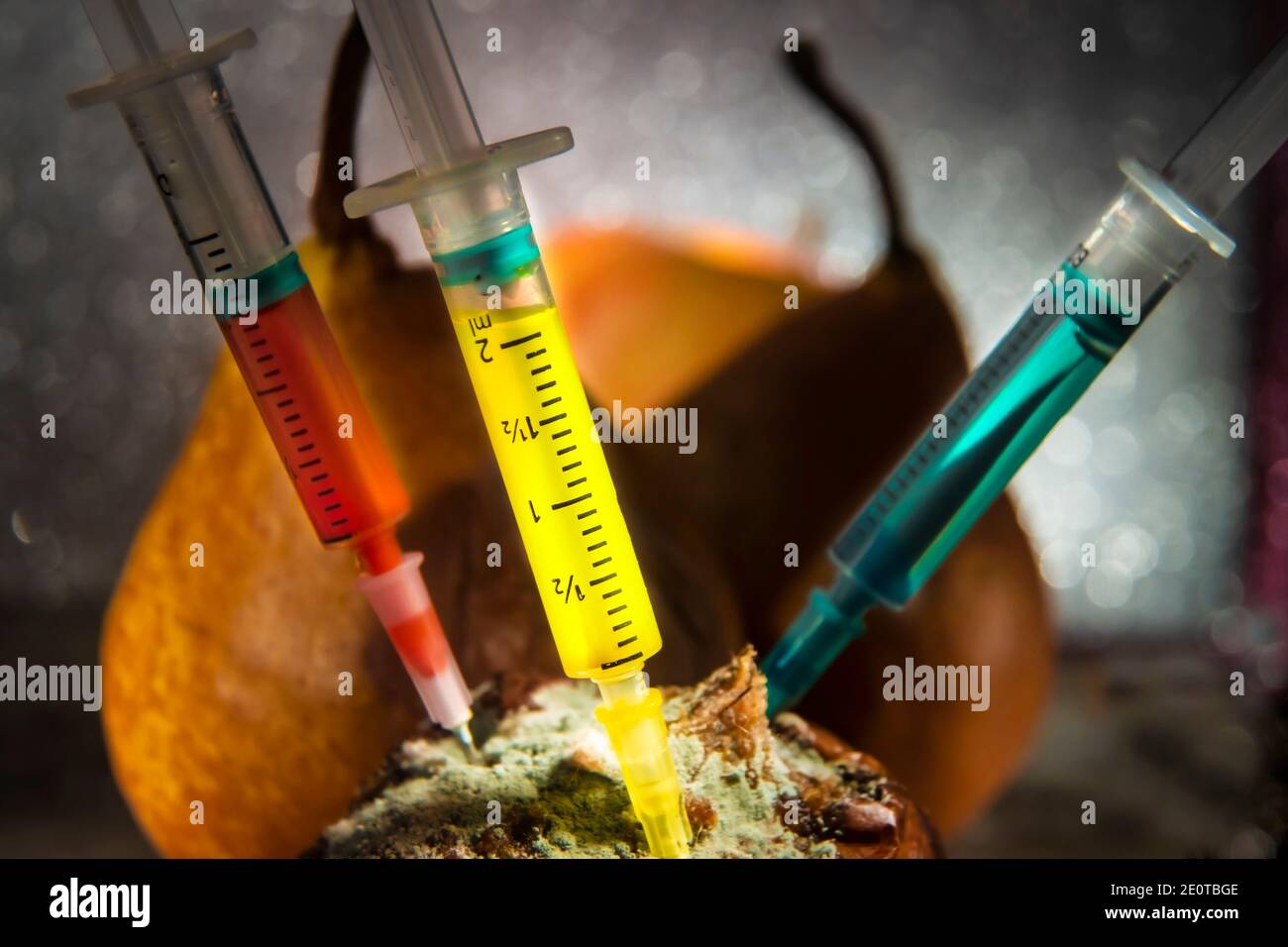 Injektionen auf Rotten Birnen Stillleben. Nahaufnahme Makrofoto. Selektiver Fokus auf gelbe Injektion. Mit Silbernem Bokeh Hintergrund.. Stockfoto